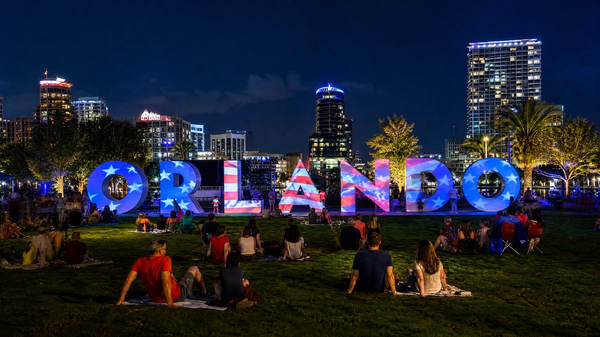 Letreiro ORLANDO iluminado com projeções patrióticas no Luminary Green Park à noite